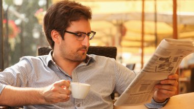 Gazeteler okuma ve kahve içme adam
