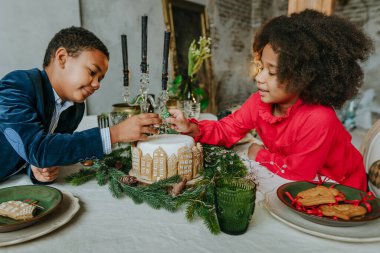 Kız ve erkek kardeş evde zencefilli kek süslüyorlar. Noel zamanı aile eğlencesi konsepti. On senelik el yapımı Mutlu yıllar tatlıları..