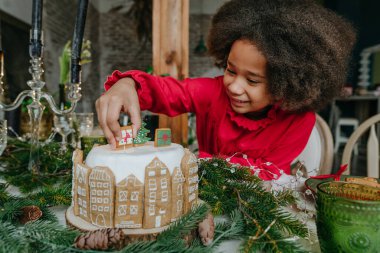 Evde zencefilli kek süsleyen kız. Noel zamanı aile eğlencesi konsepti. Küçük el yapımı mutlu yıllar tatlıları için bir fikir. Seçici odak.