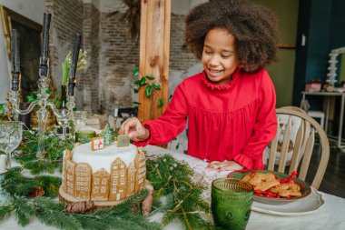El yapımı zencefilli ev ekmeğiyle süslenmiş Noel pastası tutan kız. On senelik el yapımı Mutlu Yıllar Şenlik Tatlıları.