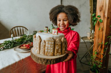 El yapımı zencefilli ev ekmeğiyle süslenmiş Noel pastası tutan kız. Küçük el yapımı yeni yıl şenlikli şekerlemeler için fikir. Kıza odaklan..