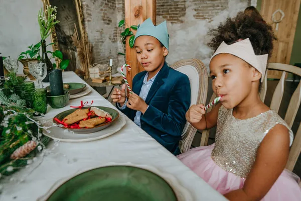Ablam ve abim Noel şekeri yiyorlar. Evdeki masada oturuyorlar..