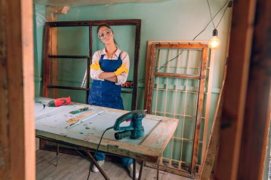 Atölyede çalışan koruyucu gözlük, eldiven ve önlük takan bir kadının portresi. Yükseltme konsepti.