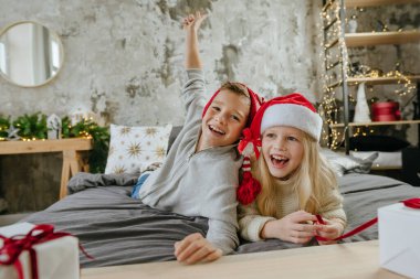 Mutlu çocuk ve kız, hediye kutularını yatakta tutarak eğleniyorlar..