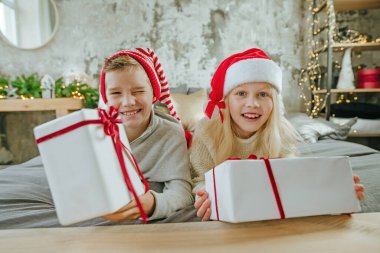 Mutlu çocuk ve kız, hediye kutularını yatakta tutarak eğleniyorlar..