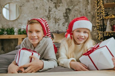 Mutlu çocuk ve kız, hediye kutularını yatakta tutarak eğleniyorlar..