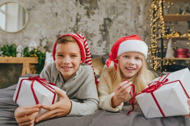 Mutlu çocuk ve kız, hediye kutularını yatakta tutarak eğleniyorlar..