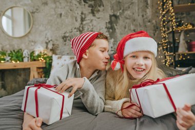 Mutlu çocuk ve kız, hediye kutularını yatakta tutarak eğleniyorlar..