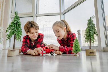 Çocuklar kırmızı oyuncak araba ve Noel hediye kutularıyla oynuyorlar..