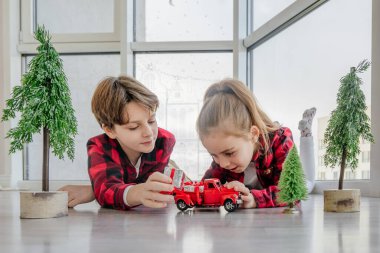 Çocuklar kırmızı oyuncak araba ve Noel hediye kutularıyla oynuyorlar..