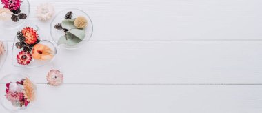 Beyaz ahşap zemin üzerinde kurumuş çiçeklerle dolu DIY süslemeleri ve metin için boş alan. Noel ağacı dekoru fikri. Üst manzara, düz yatış. Yatay panorama pankartı.