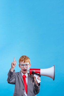 Komik kızıl saçlı genç iş adamı takım elbiseli ve mavi arka planda gözlüklü kravat takıyor ve mesaj için boş alan var.