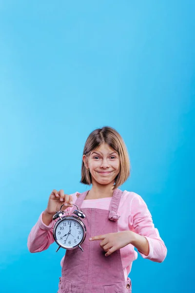 Niña Sosteniendo Reloj Apuntando Sobre Fondo Azul Con Espacio Blanco —  Fotos de Stock