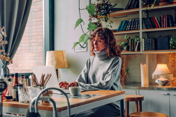 Genç kadın, klasik tarzda bir kafede dizüstü bilgisayar kullanarak çalışıyor. Seçici odak.