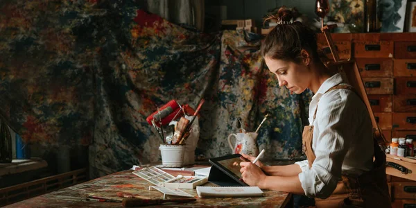 Artista feminina concentrada desenhando em sua oficina usando tablet — Fotografia de Stock