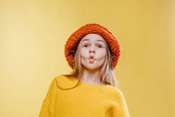 可愛いですティーン女の子身に着けていますオレンジふわふわ帽子と黄色セーターポーズ上の黄色の背景とともに空白のテキスト — ストック写真