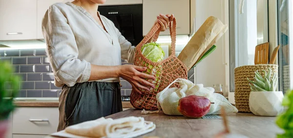 Young Woman Holding Reusable Mesh Bag Fruits Vegetables Bread Kitchen — стоковое фото