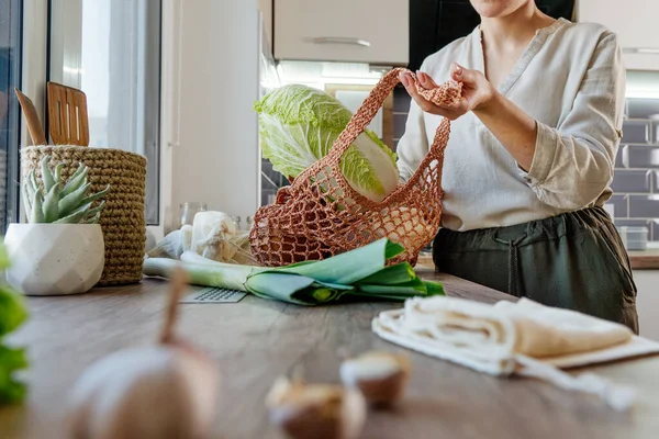 Young Woman Pulls Groceries Out Reusable Mesh Bag Kitchen Zero — стоковое фото