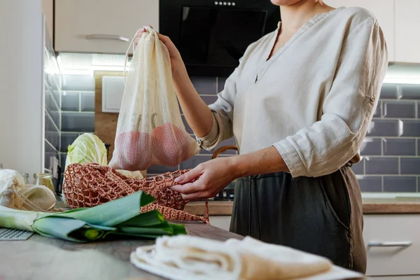 Young Woman Pulls Groceries Out Mesh Bag Kitchen Food Organic — стоковое фото