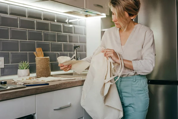 Young Woman Standing Kitchen Taking Reusable Cotton Bags Table Shopping — стоковое фото