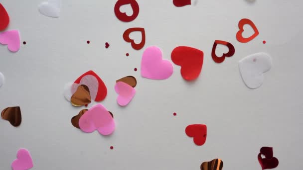 Hjärtform konfetti flyger på den vita bakgrunden — Stockvideo