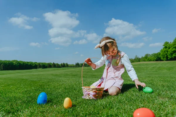 Маленька дівчинка збирає і кладе іграшкові яйця в кошик — стокове фото