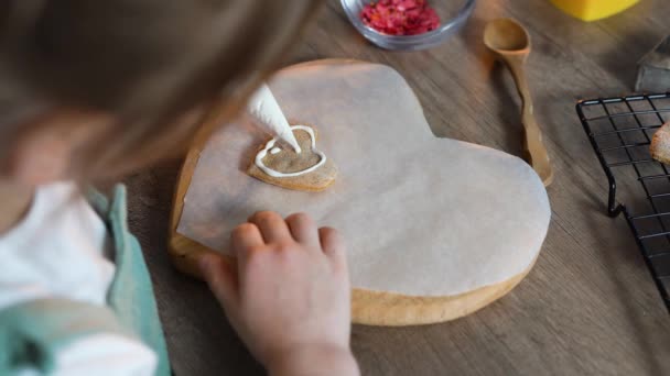 Petite fille décorant biscuits en forme de coeur faits maison — Video