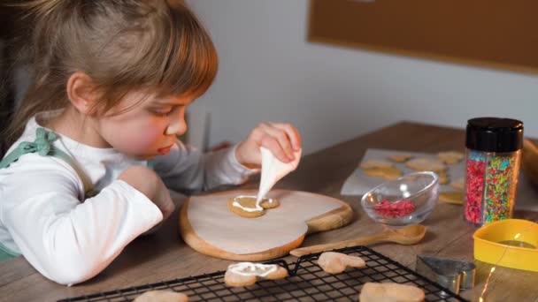 Маленькая девочка украшает домашнее печенье в форме сердца — стоковое видео