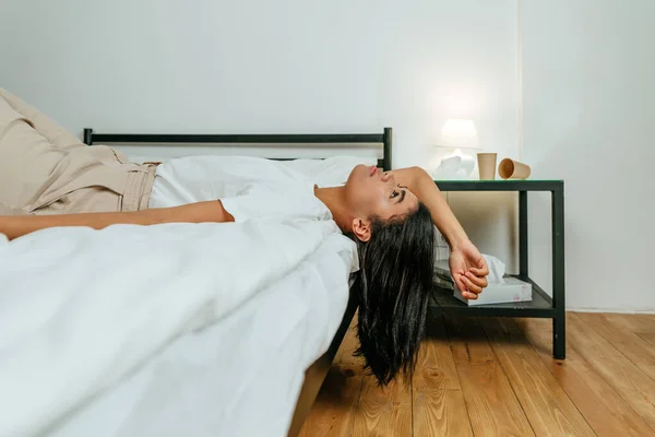 Mujer joven acostada en la cama con aspecto cansado — Foto de Stock