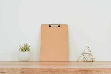 Boş ahşap pano, dekoratif metal piramit ve ahşap masa üzerindeki tencerede sulu yazı için boş alan. Konforlu minimalik ev içinin ayrıntıları.