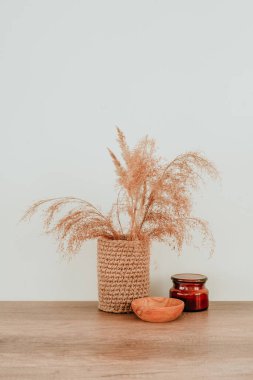 Kurumuş çiçek pampaları jute çiçek saksısında çimenler, ahşap masa üzerinde ahşap kâse ve mum ve yazı için boş alan. Ev dekorunda kullanılan doğal malzemeler. Çevre dostu kavram.
