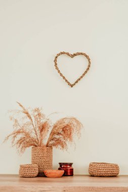 Kurumuş çiçek pampaları jüt saksısında çimenler, ahşap ve jüt kaseler ve ahşap masa üzerinde mum ve yazı için boş alan. Ev dekorunda kullanılan doğal malzemeler. Çevre dostu kavram.