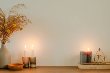 Mumlar, kurutulmuş çiçek pampaları, seramik vazodaki çimenler, ahşap masa üzerinde yazı için boş alan. Sıcak ev dekorasyonu. Çevre dostu kavram.
