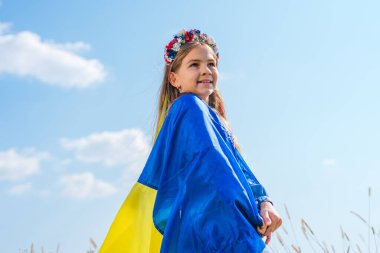 Ukrayna bayrağı taşıyan küçük kız çiçek çelengi takıyor.