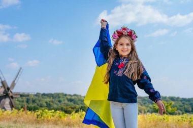 Ulusal kıyafetler ve Ukrayna bayrağı taşıyan bir kız.