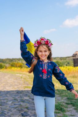 Ulusal kıyafetler ve Ukrayna bayrağı taşıyan bir kız.