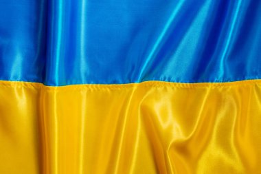 Ukrayna bayrağı geçmişi. Ukrayna 'nın kıvrımlı ulusal saten kumaş bayrağının dokusu. Üst manzara, düz uzanma.