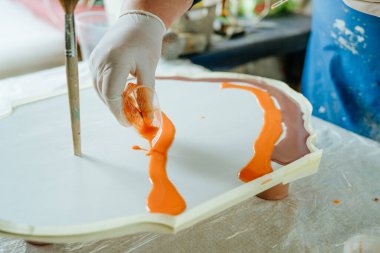 Ressam reçine sanatı tekniğinde saat yapıyor. Lastik eldiven takan kadın pigmentlerle sıvı reçine döküyor. Seçici odak.