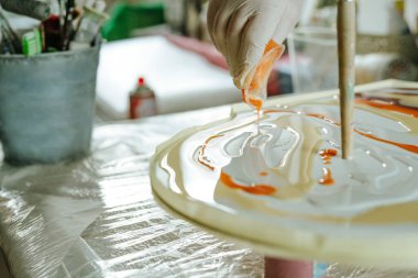 Ressam reçine sanatı tekniğinde saat yapıyor. Lastik eldiven takan kadın pigmentlerle sıvı reçine döküyor. Seçici odak.