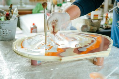 Ressam reçine sanatı tekniğinde saat yapıyor. Lastik eldiven takan kadın pigmentlerle sıvı reçine döküyor. Seçici odak.