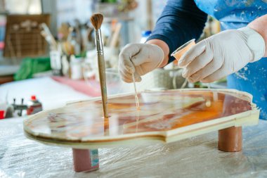 Ressam reçine sanatı tekniğinde saat yapıyor. Lastik eldiven takan kadın pigmentlerle sıvı reçine döküyor. Seçici odak.