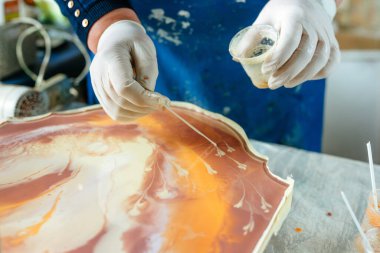 Ressam reçine sanatı tekniğinde saat yapıyor. Lastik eldiven takan kadın pigmentlerle sıvı reçine döküyor. Seçici odak.