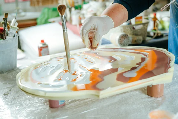 Ressam reçine sanatı tekniğinde saat yapıyor. Lastik eldiven takan kadın pigmentlerle sıvı reçine döküyor. Seçici odak.