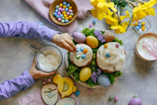 Paskalya pastalarını küçük renkli çikolata yumurtalarıyla süsleyen küçük bir kız. Şenlikli aşçılık konsepti. Düz yatıyordu.