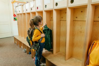 Okuldaki ya da anaokulundaki ilk günüm. Sırt çantalı küçük bir kız okuldaki bir gardıropta ceketini askıya asıyor. Okul konseptine dönelim..
