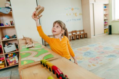 Anaokulunda ya da çocuk yuvasında tahta ovalarla oynayan küçük bir kız. Montessori eğitim kavramı.