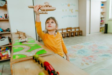 Anaokulunda ya da çocuk yuvasında tahta ovalarla oynayan küçük bir kız. Montessori eğitim kavramı.