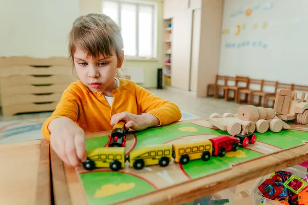 Anaokulunda ya da çocuk yuvasında tahta trenle oynayan küçük bir kız. Montessori eğitim kavramı.