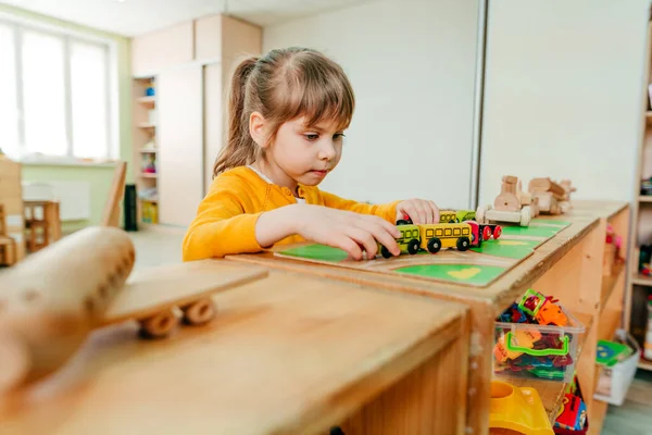 Anaokulunda ya da çocuk yuvasında tahta trenle oynayan küçük bir kız. Montessori eğitim konsepti. Seçici odak.
