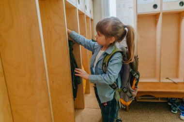 Okuldaki ya da anaokulundaki ilk günüm. Sırt çantalı küçük bir kız okuldaki bir gardıropta ceketini askıya asıyor. Okul konseptine dönelim..